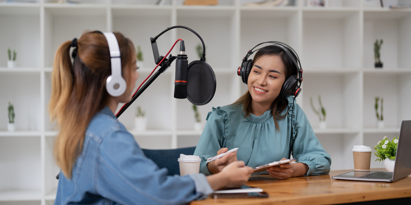 Female host recording radio podcast interview with guest at home